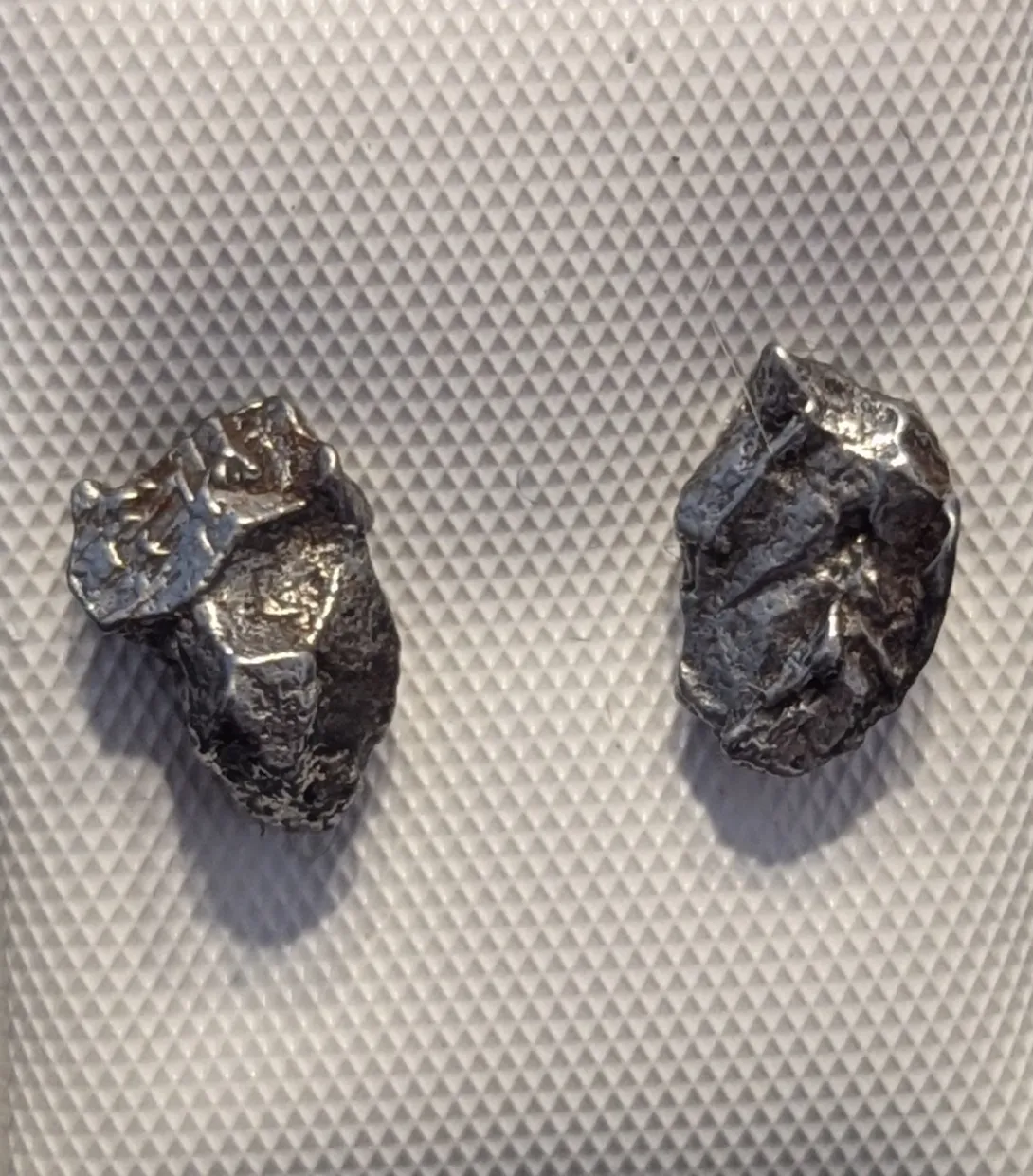 A pair of earrings made from meteorite fragments